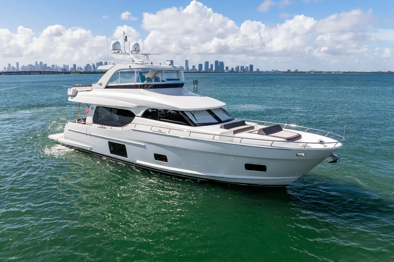 Slide: The Image of 2021 Ocean Alexander 70E Motoryacht cruising on open water with city skyline backdrop. - 11
