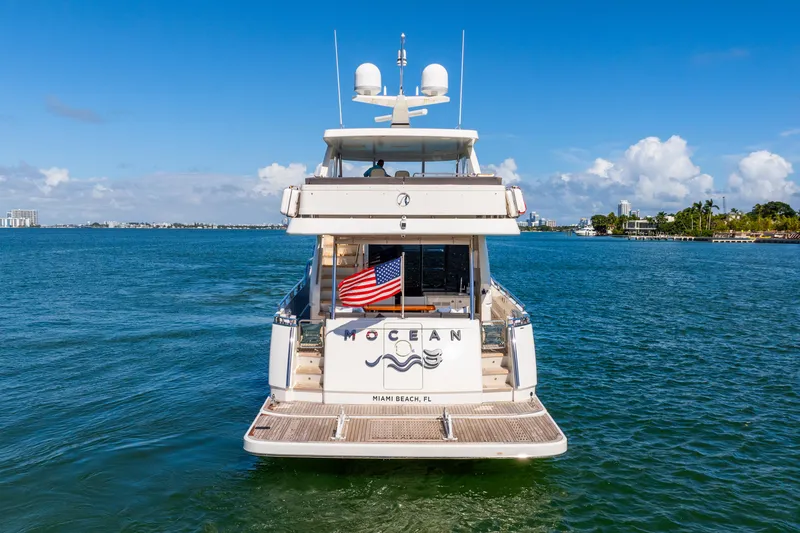 Slide: The Image of 2021 Ocean Alexander 70E Motoryacht on open water, rear view with American flag. - 15