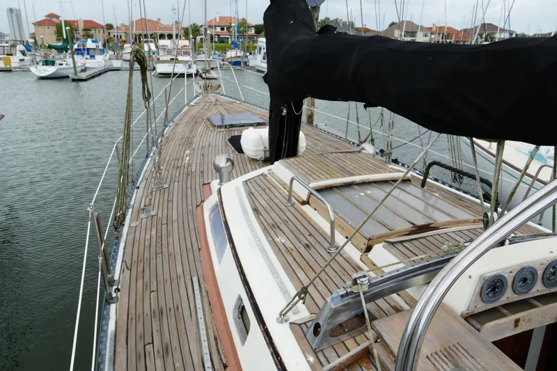 Slide: The Image of 1980 Lafitte 44 Cutter sailboat docked in marina, showcasing wooden deck and rigging. - 10