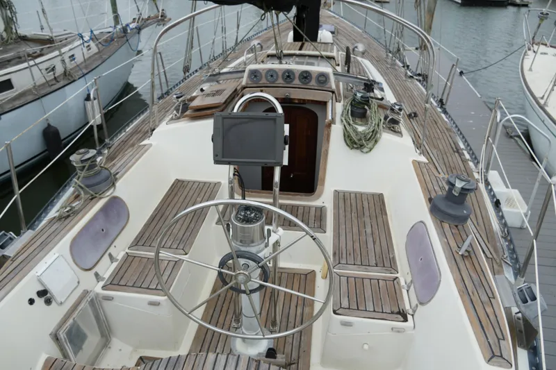 Slide: The Image of 1980 Lafitte 44 Cutter sailboat deck with wooden seating and steering wheel. - 13