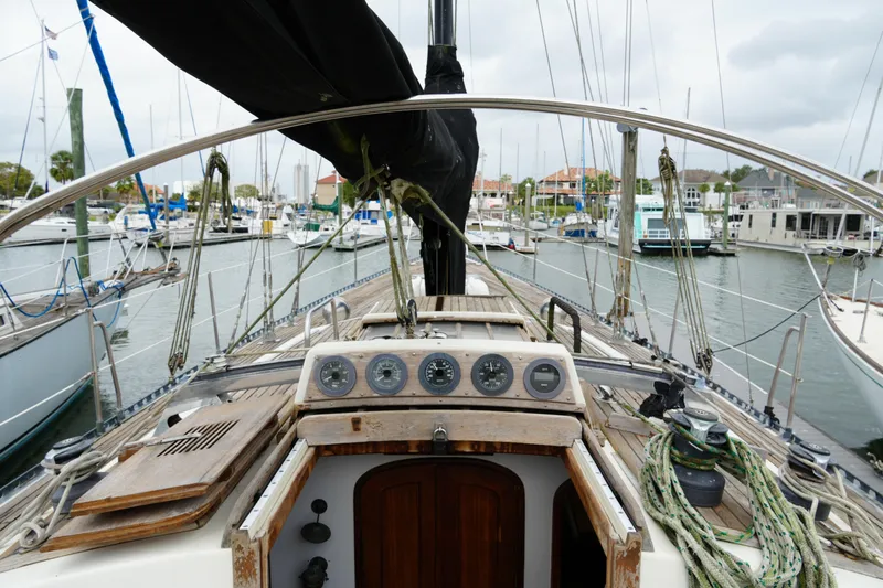 Slide: The Image of 1980 Lafitte 44 Cutter sailboat docked in a marina, showcasing its cockpit and navigation instruments. - 16