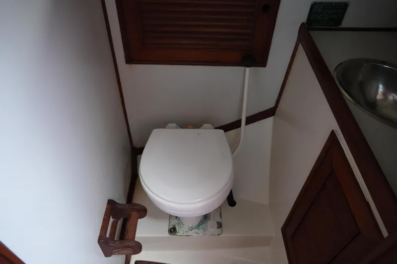 Slide: The Image of 1980 Lafitte 44 Cutter yacht bathroom with toilet and wooden accents. - 22