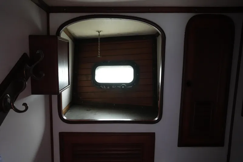 Slide: The Image of Interior of 1980 Lafitte 44 Cutter, featuring a porthole and wooden cabinetry. - 24