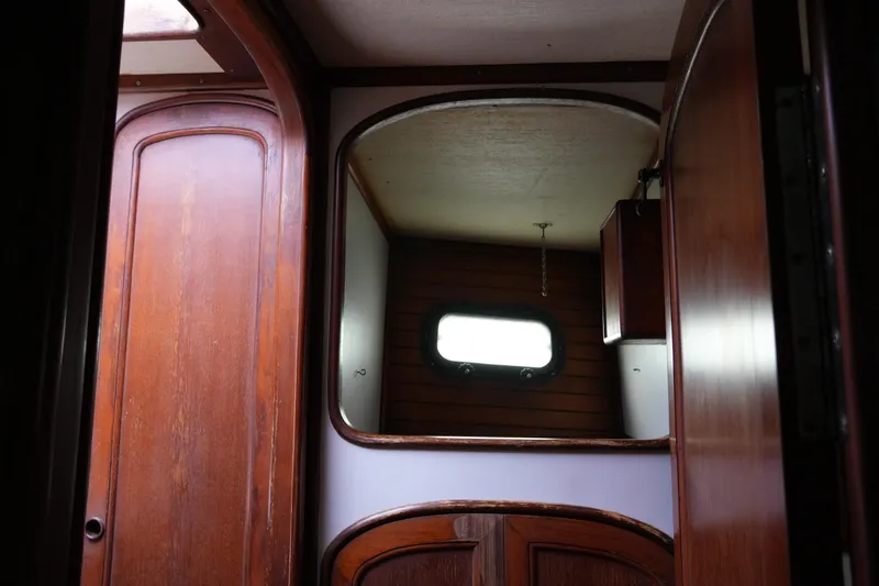 Slide: The Image of Interior of 1980 Lafitte 44 Cutter sailboat with wooden cabinetry and porthole window. - 26