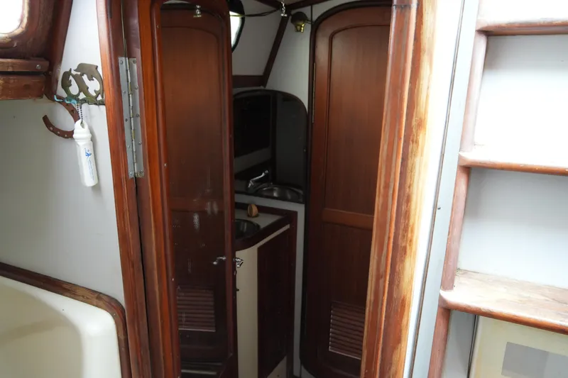 Slide: The Image of Interior of 1980 Lafitte 44 Cutter sailboat, featuring wooden cabinetry and compact design. - 36