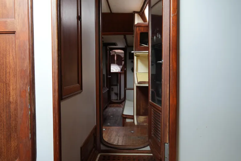 Slide: The Image of Interior view of 1980 Lafitte 44 Cutter sailboat, featuring wooden cabinetry and narrow passageway. - 44