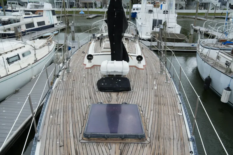 Slide: The Image of 1980 Lafitte 44 Cutter sailboat docked, showcasing wooden deck and marina surroundings. - 7