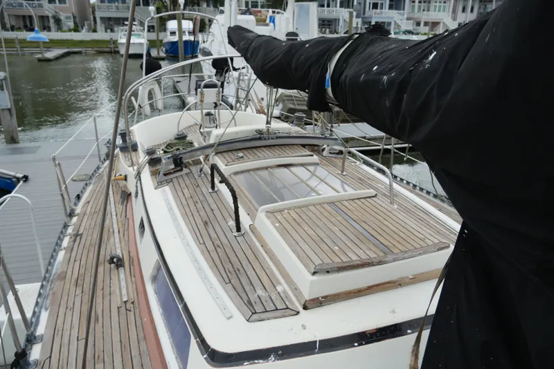 Slide: The Image of 1980 Lafitte 44 Cutter sailboat docked, showcasing wooden deck and covered mast. - 9