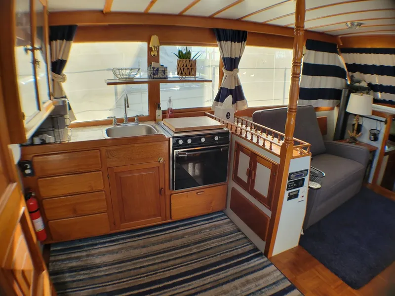 Slide: The Image of 1981 Roughwater 41 Pilot House interior with kitchen, striped curtains, and cozy seating area. - 21