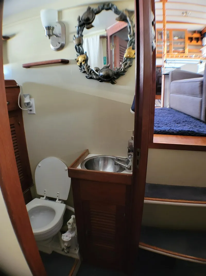 Slide: The Image of 1981 Roughwater 41 Pilot House bathroom with toilet, sink, and nautical decor. - 27