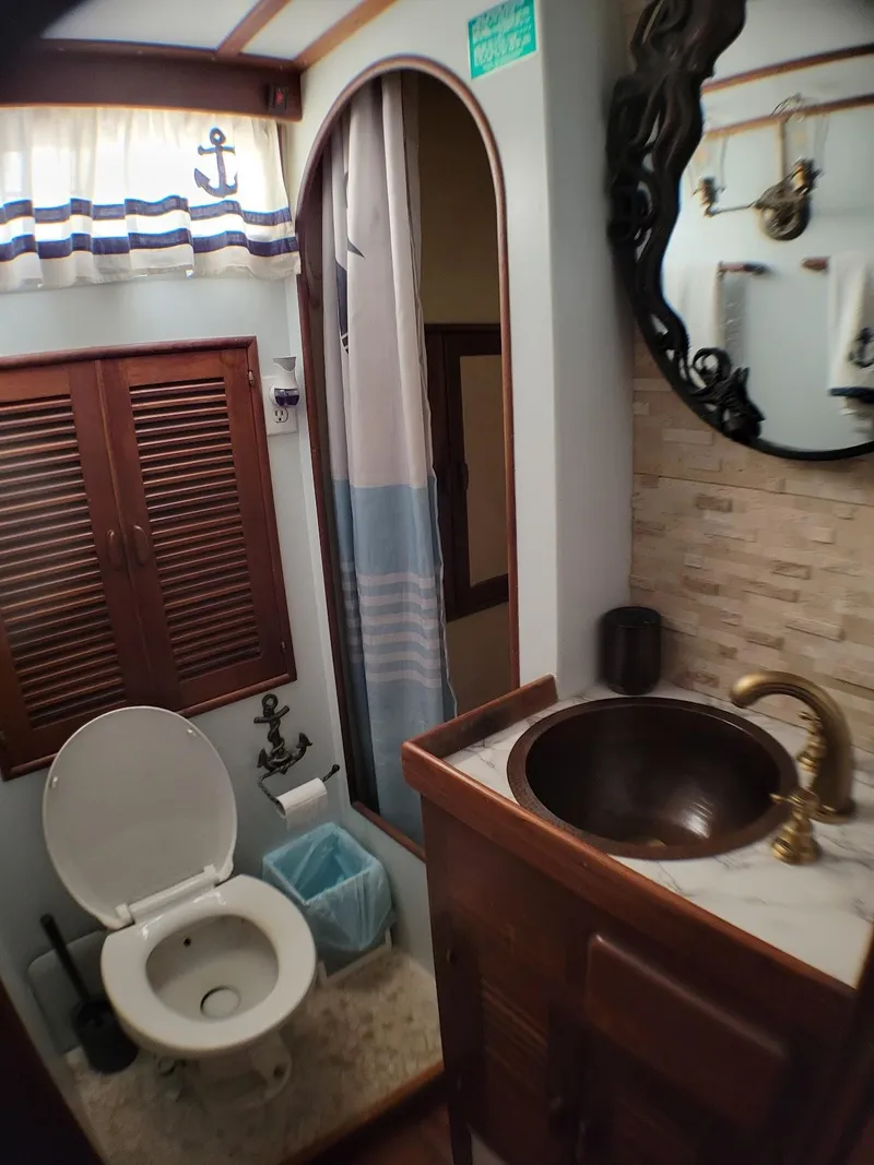 Slide: The Image of 1981 Roughwater 41 Pilot House bathroom with nautical decor, featuring a toilet, sink, and shower. - 36