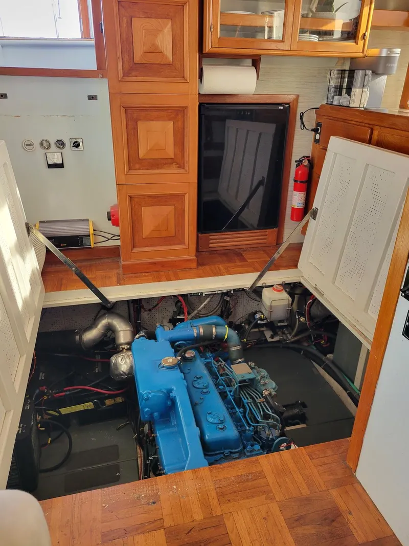 Slide: The Image of Engine room of 1981 Roughwater 41 Pilot House with blue engine and wooden cabinetry. - 39