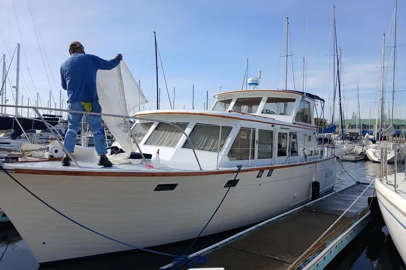 Slide: The Image of 1981 Roughwater 41 Pilot House yacht docked, person handling sail, marina background. - 4