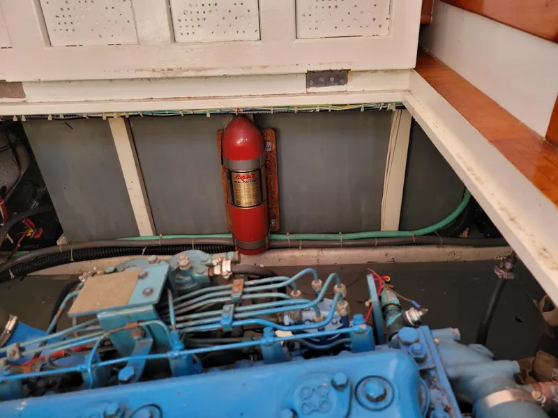 Slide: The Image of Engine room of 1981 Roughwater 41 Pilot House with fire extinguisher and blue engine components. - 41