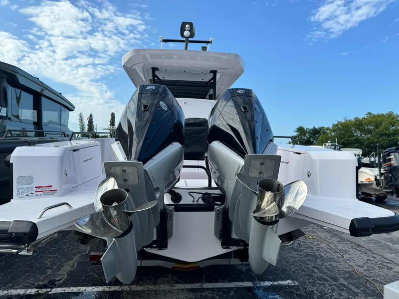 Slide: The Image of 2024 Axopar Sun Top boat with dual outboard engines, docked under a clear sky. - 11