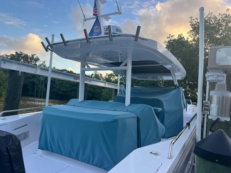 Slide: The Image of 2024 Axopar Sun Top boat docked with blue covers, surrounded by trees and a sunset sky. - 19