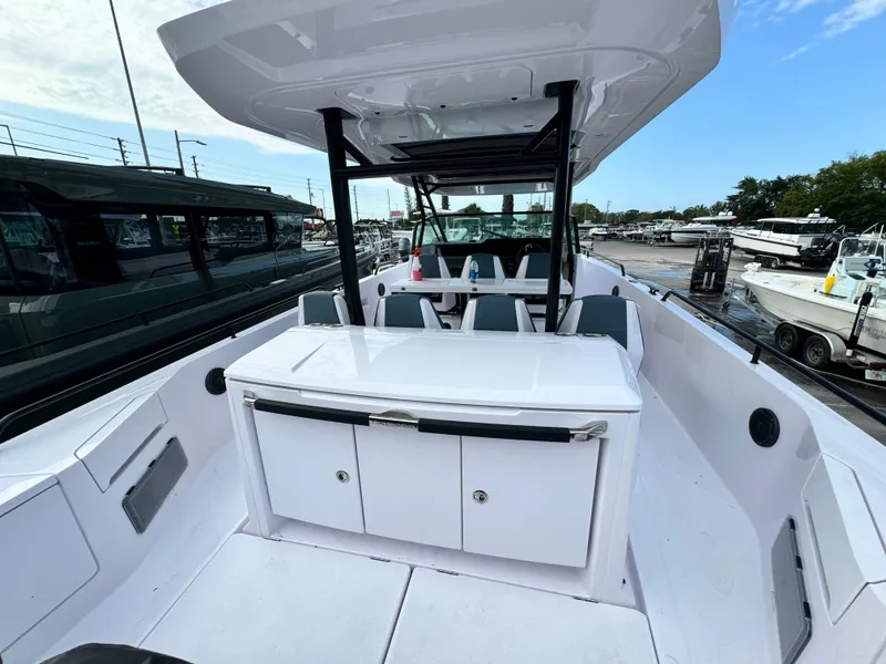 Slide: The Image of 2024 Axopar Sun Top boat interior with seating and storage, docked at a marina. - 9