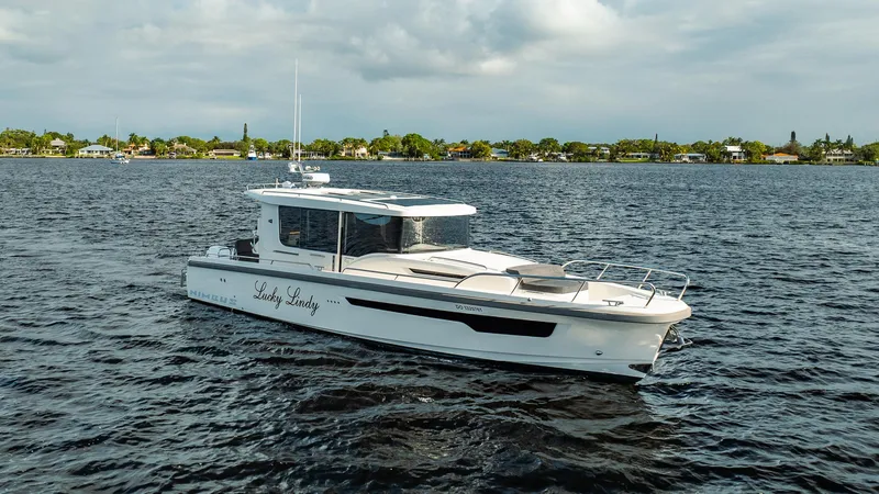 Slide: The Image of 2023 Nimbus Commuter 11 boat cruising on a calm lake under cloudy skies. - 2