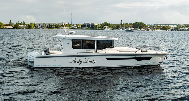 Slide: The Image of 2023 Nimbus Commuter 11 boat named "Lucky Lindy" cruising on a calm waterway. - 5