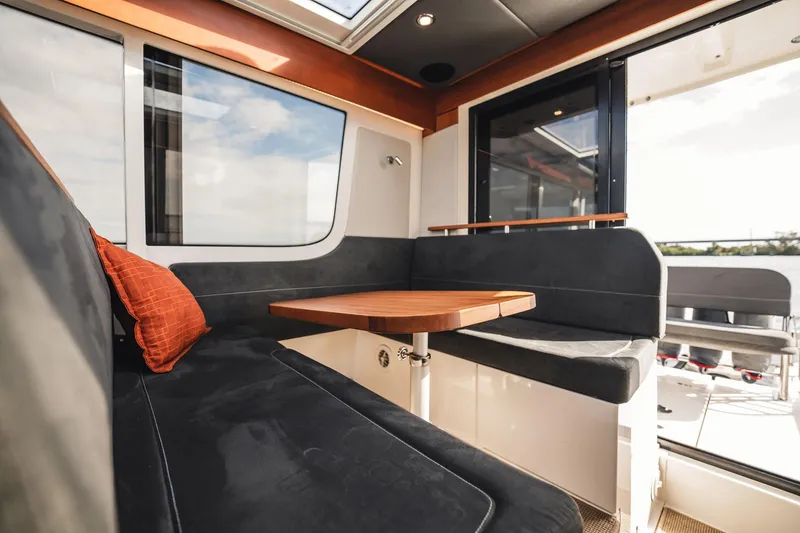 Slide: The Image of Interior of 2023 Nimbus Commuter 11 boat with cozy seating and wooden table. - 6