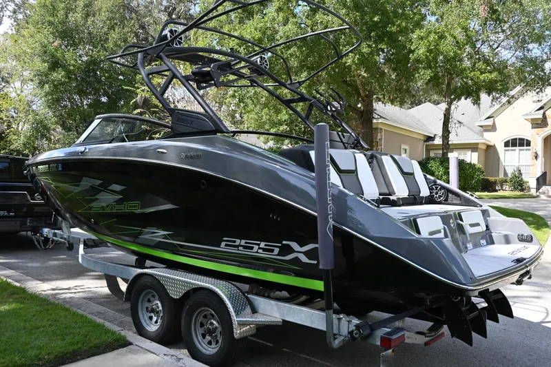 The Image of 2021 Yamaha Boats 255XD on trailer, sleek black design, parked in residential area. - 0
