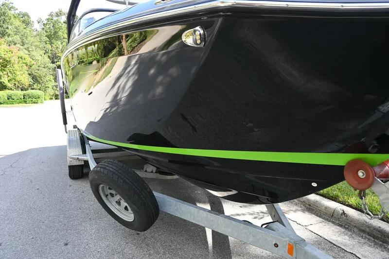Slide: The Image of 2021 Yamaha Boats 255XD on trailer, black hull with green stripe, parked on street. - 39