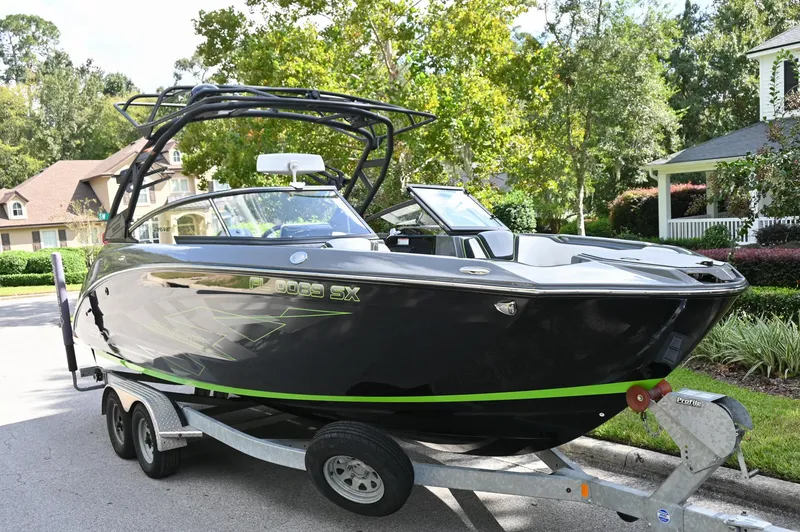 Slide: The Image of 2021 Yamaha Boats 255XD on trailer, sleek black design with green accents, parked in residential area. - 47