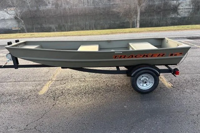The Image of 2025 Tracker Grizzly 1236 Utility boat on trailer, parked near a river. - 0