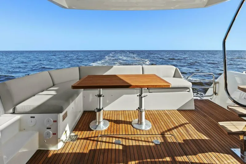 Slide: The Image of Luxury 2022 Prestige 460 yacht deck with wooden table and ocean view. - 9