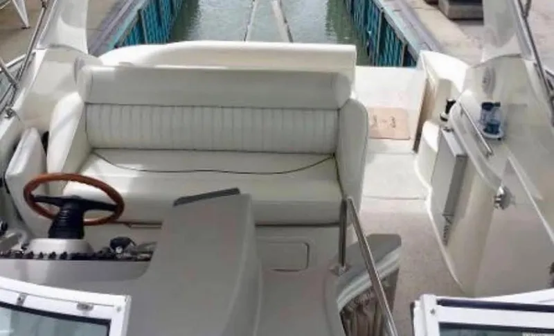 Slide: The Image of 2001 Cruisers Yachts 3075 Express interior with white seating and wooden steering wheel. - 11