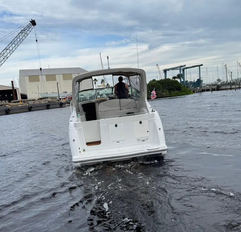 Slide: The Image of 2000 Maxum 3000 SCR boat cruising in a marina with industrial backdrop. - 3