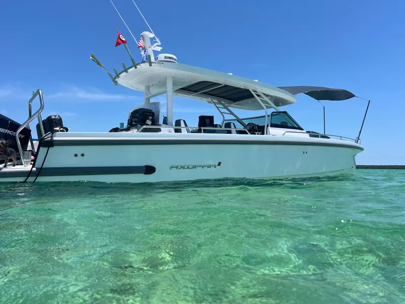 Slide: The Image of 2024 Axopar Sun Top boat on clear turquoise water under blue sky. - 0