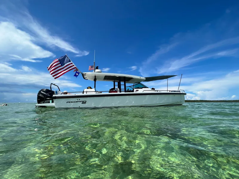 Slide: The Image of 2024 Axopar Sun Top boat on clear water with American flag. - 1