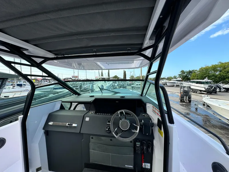 Slide: The Image of 2024 Axopar Sun Top boat cockpit with steering wheel and dashboard, docked outdoors. - 15