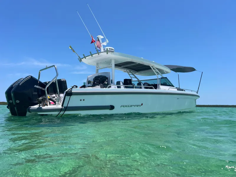 Slide: The Image of 2024 Axopar Sun Top boat on clear turquoise water under blue sky. - 2