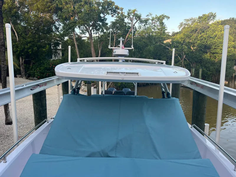 Slide: The Image of 2024 Axopar Sun Top boat with blue cover, docked near lush greenery. - 22