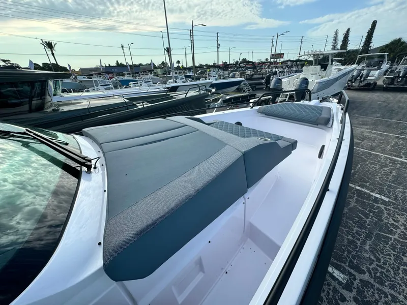 Slide: The Image of 2024 Axopar Sun Top boat with sleek design and spacious deck in a marina setting. - 5