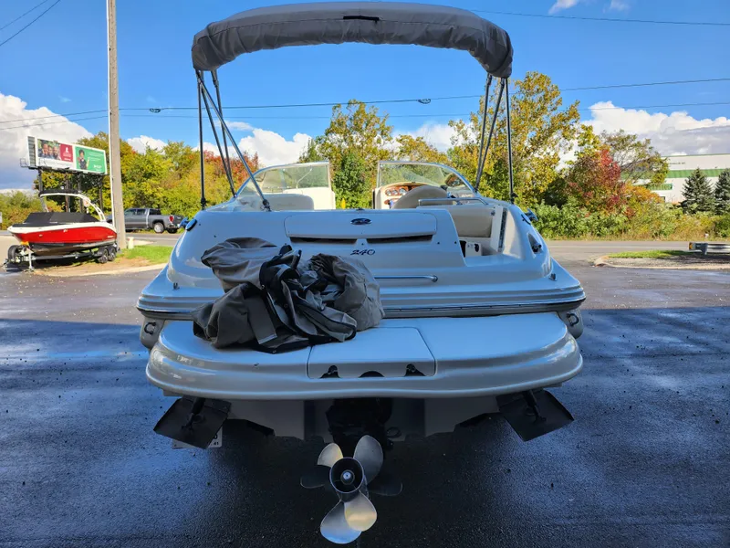 Slide: The Image of 2002 Sea Ray 240 Sundeck boat with canopy, parked outdoors on a sunny day. - 2