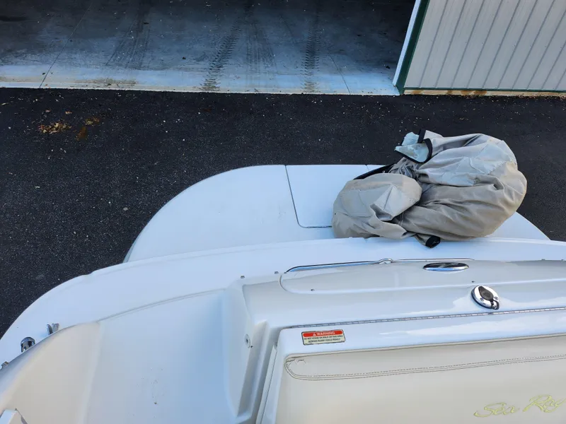 Slide: The Image of 2002 Sea Ray 240 Sundeck boat with cover on deck, parked near a garage. - 25