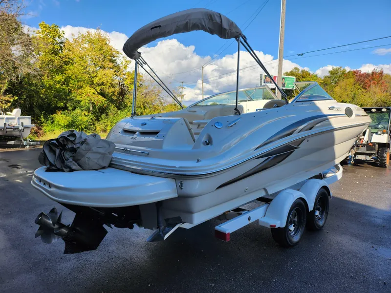 Slide: The Image of 2002 Sea Ray 240 Sundeck boat on trailer, parked outdoors under blue sky. - 3