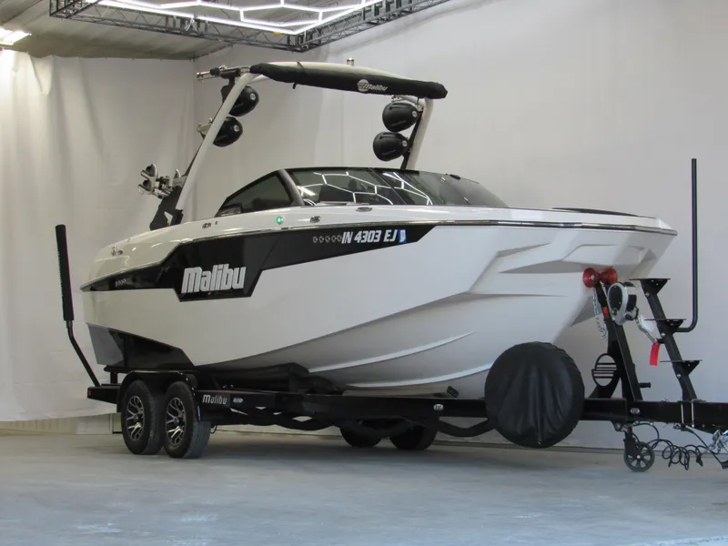 Slide: The Image of 2022 Malibu M220 boat on trailer in indoor showroom. - 1
