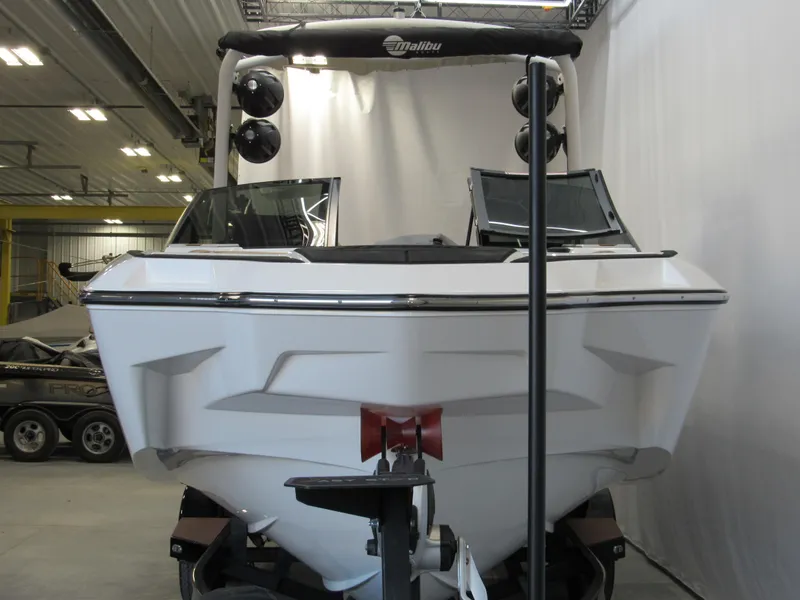 Slide: The Image of 2022 Malibu M220 boat in a showroom, front view with speakers and windshield. - 2