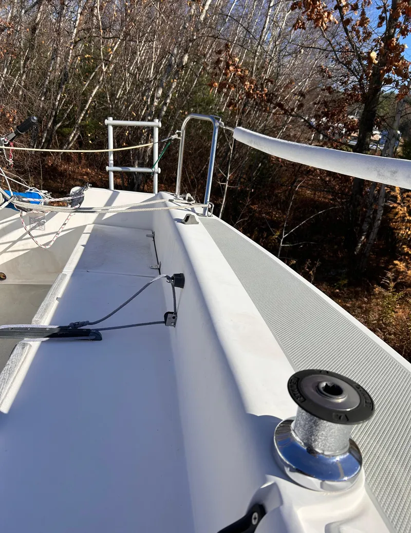 Slide: The Image of 1987 Catalina 22 Capri sailboat deck with winch, surrounded by autumn trees. - 16