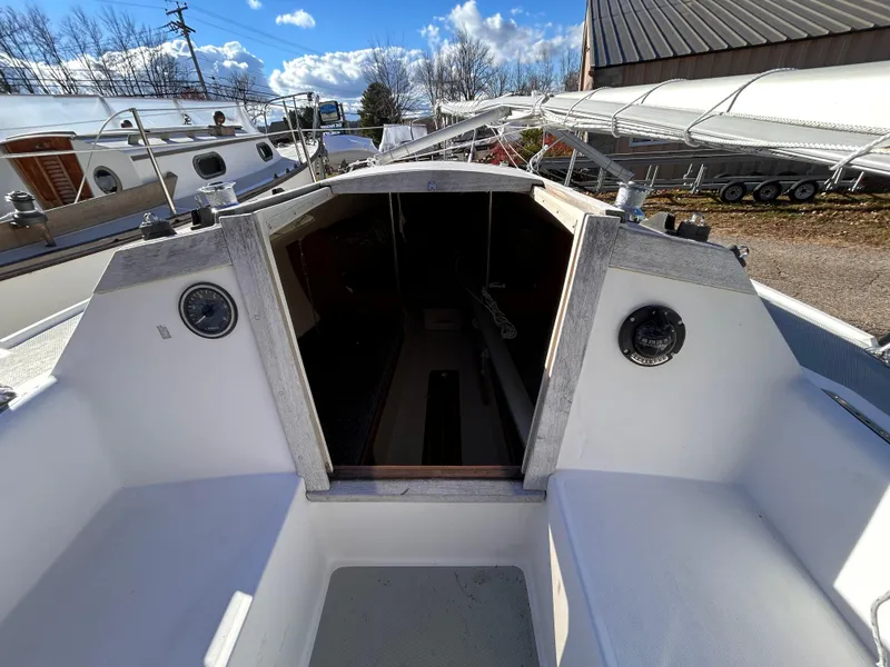 Slide: The Image of 1987 Catalina 22 Capri sailboat cockpit with open cabin, docked under blue sky. - 26