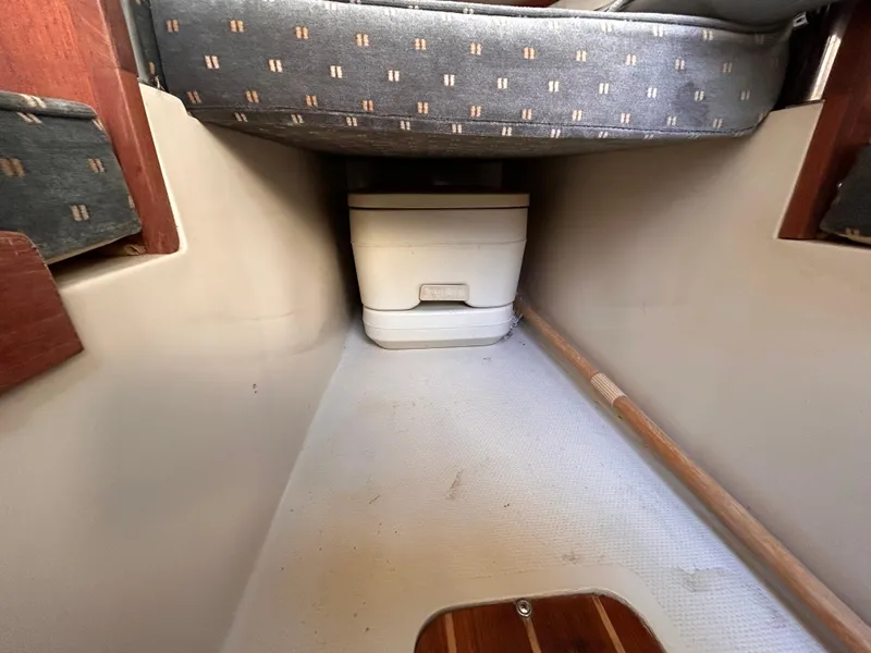 Slide: The Image of 1987 Catalina 22 Capri cabin interior with portable toilet and cushioned seating. - 36