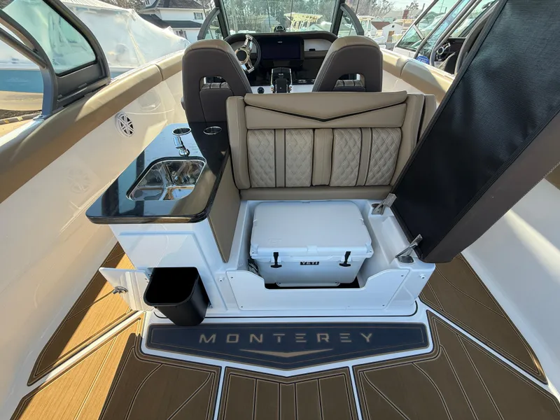 Slide: The Image of 2025 Monterey Elite 30 OB interior with seating, sink, and cooler on deck. - 12