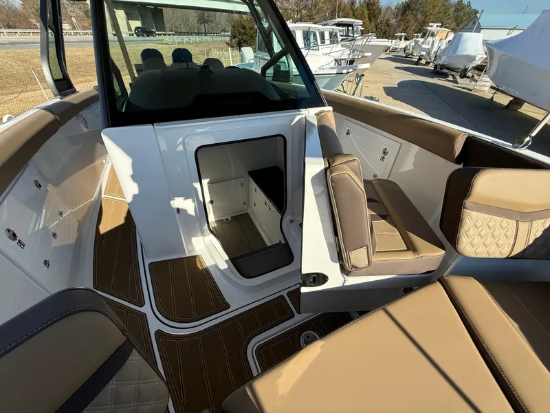 Slide: The Image of 2025 Monterey Elite 30 OB boat interior with tan seating and open cabin door. - 25