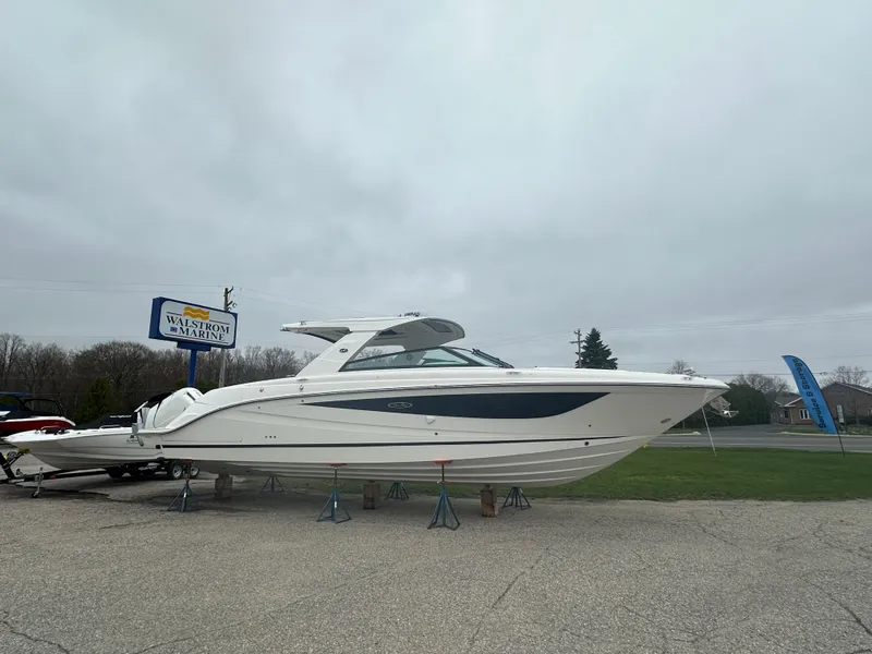 The Image of 2025 Sea Ray SLX 400 OB boat displayed on stands outdoors. - 0