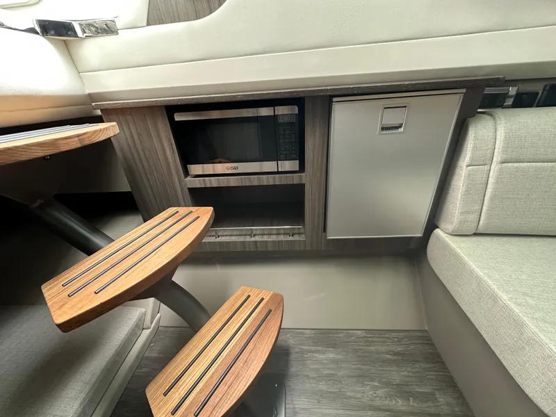 Slide: The Image of 2025 Sea Ray SLX 400 OB interior with microwave, compact fridge, and wooden steps. - 21