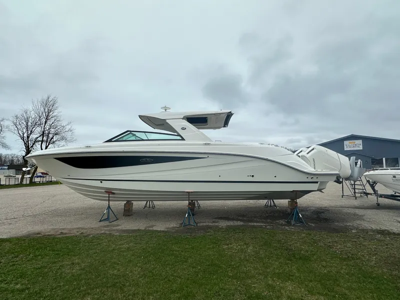 Slide: The Image of 2025 Sea Ray SLX 400 OB boat on stands, overcast sky, grassy foreground. - 4